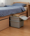 Heavy Duty Stackable Storage Totes With Secure Hinged Lids And Smooth Rolling Casters Plus Reinforced Side Handles For Clutter Free Closet Organization And Dorm Spaces under bed storage with books on top.