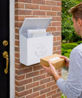 Man placing package in Outdoor Wall Mount Mailbox 11.5 x 5 x 13 Inches White Waterproof Heavy Duty Metal Mailbox for Outside, mounted on brick wall.