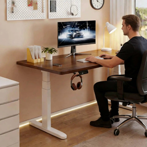 Smooth Riding Electric Height Adjusting Standing Desk With Touch Memory Presets And Heavy Duty Anti Collision Technology Created As A Reliable Gaming Computer Table For Hassle Free Home Office Setups Around Twenty Eight By Fifty Five Inches features a man working at a solid wood desk.