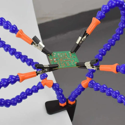 Ultimate Soldering Helping Hands Clamp with 4 precision alligator clips holding a circuit board for electronics repair and DIY arts.