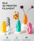 Colorful vases made from Silk PLA Filament 1.75mm For 3D Printers, Ultra Gloss Silk Finish, displayed on white pedestals.