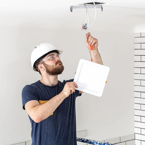 Man installing light with Six Pack Universal Light Fixture Mounting Bracket Square Kit for Ceiling or Wall, adjustable crossbar visible