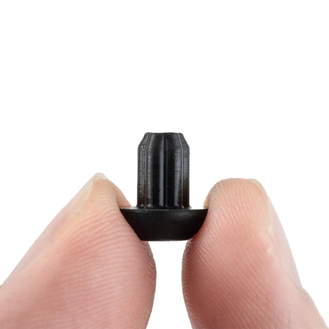Close-up of a Grate Rubber Feet Replacement for Cooktop Burners, heat-resistant rubber foot pad, held between two fingers.