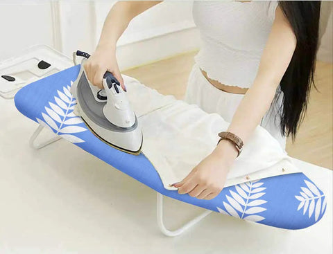 Woman ironing on 12.5 X 32 Inch Mini Ironing Board Cover With 100 Percent Cotton Cover And Extra Thick Pad That Keeps It Real Resists Scorching And Staining Fits Small Tabletop Ironing Boards Not Included, blue and white leaf design.