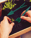 Gardener using the 7 Piece Mini Seed Spreader Tool Set For Precise Seed Dispensing And Easy Garden Planting with dibber and widger