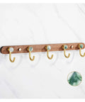 Rock Solid Wall Mounted Coat Rack With Five Heavy Duty Hooks And Natural Wood Base on wall with golden hooks and green accents.
