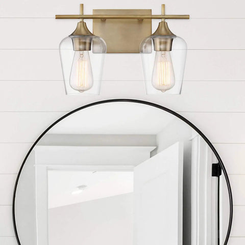 Dope Octave Bohemian Clear Glass Vanity Wall Light Two Light Bath Fixture In Warm Brass installed over round mirror