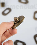 Framendino metal bag turn-lock clasp in antique brass finish, close-up view