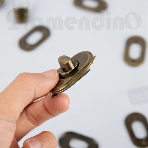 Framendino metal bag turn-lock clasp in antique brass finish, close-up view