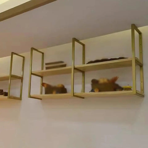 Hella Sturdy Badass Heavy Duty Floating Shelf Brackets in gold supporting wooden shelves in a dining area.