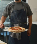 Ooni 12-inch aluminum pizza peel with handle carrying a pizza in a home kitchen.