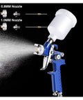 Pro Level Pneumatic Paint Spray Gun With One Millimeter Nozzle spitting even mist, clear fluid jar and blue trigger handle.