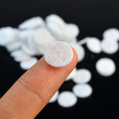 Close-up of a single 10 mm microdermabrasion cotton filter on a fingertip, part of 200 Pcs Microdermabrasion Cotton Filters Replacement 10 mm Universal Fit Diamond Dermabrasion Vacuum Filters for Suction Machines Soft Skin Friendly Sponge Filters for Home Spa Facial Care White.