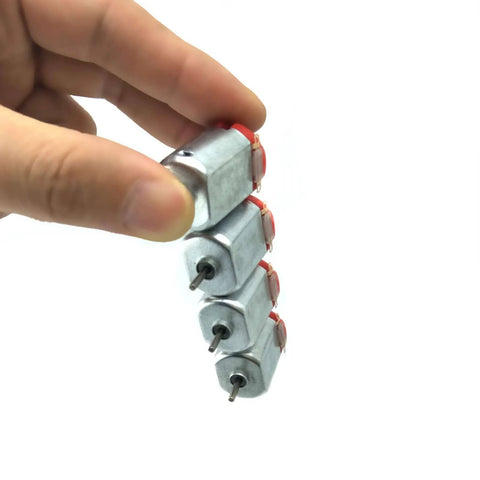 Hand holding stack of four silver metal shell 10 Pack Micro 130 DC Brushed Motors 3V To 12V, High Speed 9,000 To 25,000 RPM No Load