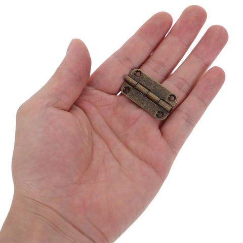 Hand holding Antique Bronze Iron Hinges Set With Four Hole Vertical Mount Small Round Corner Cabinet Hinges 12 Pack 1.38 x 0.71 x 0.16 In