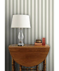 Grain Sack Stripe PVC Free Wallpaper Featuring Refined Linen Texture in a room with a wooden table and lamp.