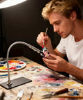 Person using Magnetic Helping Hands Soldering Tool With Flexible Alligator Clip Arms And Magnetic Base for detailed painting project.