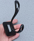 Vintage Matte Black Wall Hooks Set Of Five For Hanging Heavy Coats Umbrellas And Handbags Boasts Dope Industrial Vibes And Rock Solid Screw Mount Hardware held in hand showing hook design.