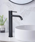 Go-To Matte Black Vessel Sink Faucet Tall And Sleek For 1 Hole Mount 360 Degree Swivel Single Handle Mixer Spout Stainless Steel Bathroom Faucet With Pop Up Drain next to white basin on marble counter