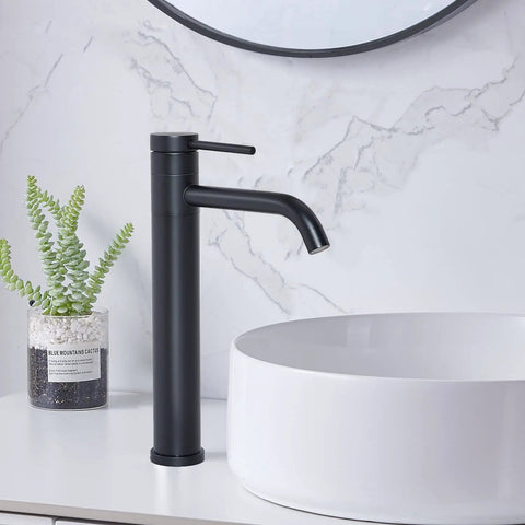 Go-To Matte Black Vessel Sink Faucet Tall And Sleek For 1 Hole Mount 360 Degree Swivel Single Handle Mixer Spout Stainless Steel Bathroom Faucet With Pop Up Drain next to white basin on marble counter