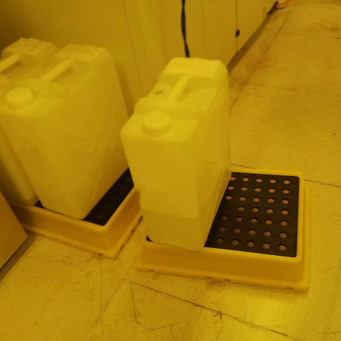 Yellow Nestable Spill Pallet For Oil Drums Leak Proof Drum Containment Tray shown with containers in garage storage setup.