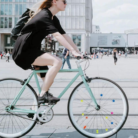 Urban cyclist with 216 Piece Assorted Colors Bike Spoke Beads Clips Set For Wheel Decorations on bike wheels.