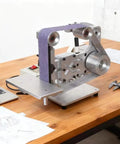 Powerhouse 750W Belt Sander With 915X50mm Sanding Belt For Metal And Wood Projects on a wooden table with sketches.