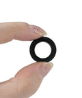 Close-up of a single black nylon flat washer from the 750 Piece Nylon Flat Washers Set For Screws Bolts 7 Sizes Black Plastic Washers Assortment Kit For Household And Commercial Use M3 To M12 Great For Furniture Repair Appliances Automotive Plumbing And DIY Projects held between fingers.
