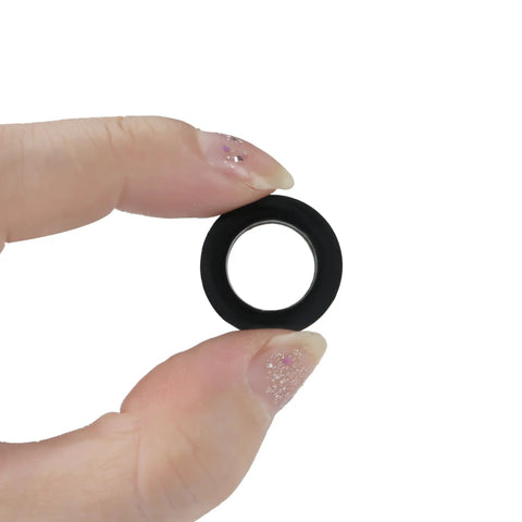 Close-up of a single black nylon flat washer from the 750 Piece Nylon Flat Washers Set For Screws Bolts 7 Sizes Black Plastic Washers Assortment Kit For Household And Commercial Use M3 To M12 Great For Furniture Repair Appliances Automotive Plumbing And DIY Projects held between fingers.