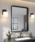 Chill Out Matte Black Milk Glass Wall Sconces Bringing Soft Warm Light To Your Space Premium Metal Build Rust Resistant Finish above a modern bathroom sink.