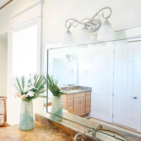 Powell Collection Four-Light Bathroom Vanity Fixture In Classic Nickel above a mirror in a bright bathroom setting.