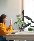 Woman using Heavy Duty Dual Monitor Desk Mount For 17 To 32 Inch Screens Featuring Gas Spring Height Adjustment in home office.