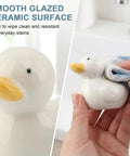 Upgrade Your Lavatory Style With These Dope Duck Toilet Bolt Covers And Slick Ceramic Screw Caps That Hit Different For Instant Bathroom Vibe Quick Install Two Pack For A Crisp Clean Finish. Smooth white ceramic duck being wiped clean.
