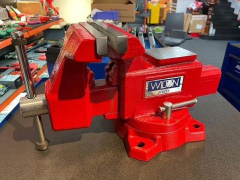 Beefy Utility Bench Vise With Five And A Half Inch Jaw Width And Five Inch Jaw Opening Three And A Quarter Inch Throat Dual Lock Downs 360 Degree Swivel Base Replaceable Hardened Serrated Jaws Powder Coat Finish Built In Pipe Jaws And Large Anvil on workbench