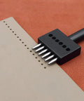 Close-up of Durable Leather Hole Punch Tool Set, 3 Piece Prong Punch Kit with 6 Prongs creating round holes in leather DIY project.
