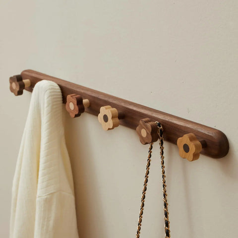 Dang Cute Flower Peg Wall Mount Coat Rack For Kids Crafted From Solid Walnut Wood Storage hanging a white sweater on flower hooks.