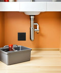 Slick Black Plastic Wall Access Panel Swings Open For Easy Inspections under sink with gray storage bin.