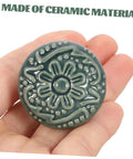 Hand holding a single knob from Set Of 10 Ceramic Drawer Pulls And Kitchen Cupboard Knobs With Vintage Pattern Single Hole Cabinet Door Handles For Dresser And Closet Hardware In Celadon Blue