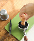Hand using 58mm Portafilter Cleaning Brush For Espresso Machines Pro Barista Tool With Arc Bristle Design on portafilter