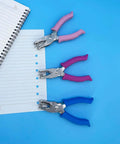 Three 1/4 Inch Hole Punchers for Crafts with soft grips in pink, purple, and blue, next to punched notebook paper on a blue background.