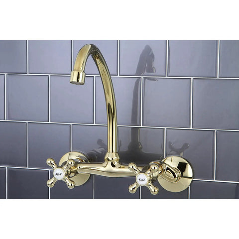 Gold wall mounted kitchen faucet with cross handles on a gray tiled backsplash