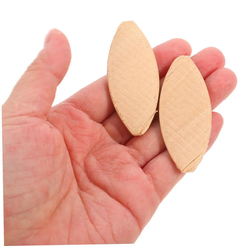 Premium 100 Pack Woodworking Biscuits For Slotting Machines, two beechwood biscuits held in hand for framing connectors.