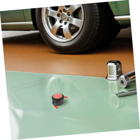 Low Key No Stress Automatic Aerosol Fire Extinguisher 2 Pack with Heavy Duty Back Adhesive on garage floor near vehicle.