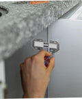 Silver metal wardrobe hinge repair kit being installed on cabinet door with screwdriver