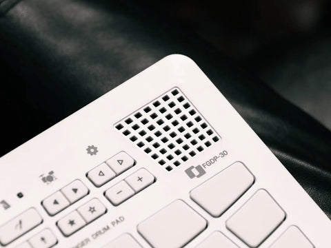 Close-up of a Compact Finger Drum Pad with 18 touch sensitive pads, built-in sounds, USB connectivity, integrated speaker, rechargeable battery.