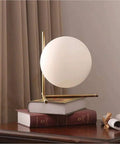 Mid Century Modern Brass Table Lamp With Gold Glass Globe Contemporary Desk Light on books in cozy home setting