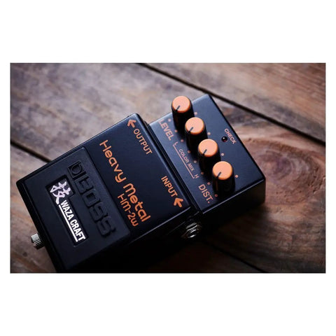 Waza Craft HM-2W Heavy Metal Guitar Pedal with orange knobs on a wooden surface, delivers legendary chainsaw tone.
