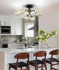 Modern kitchen with Bold Black Chandelier Lighting With Glass Orbs above a white island, featuring wooden chairs.