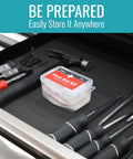 Front view of a clear DMI 76-piece first-aid kit with a red label in a tool-drawer.