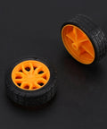 Two orange and black plastic tires from the 78 Piece Gear Kit For DIY RC Cars And Robots Module 0.5 Small Gears With Axles Tires And Bushings.
